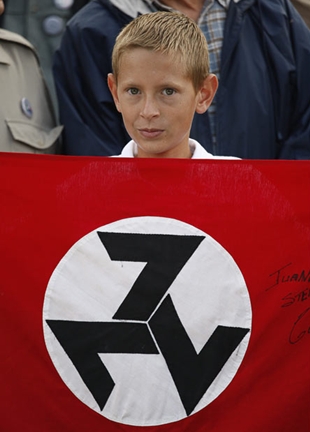 Cativo na manifestación coa bandeira do AWB, tres setes formando unha esvástica